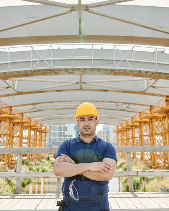 A construction worker with crossed arms on a job site