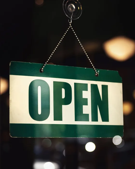 A green open sign hanging in a shop window