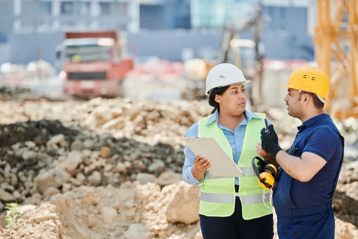 Two builders in hard hats reviewing plans on site