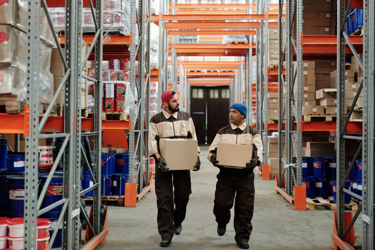 Warehouse team reviewing stock under tall pallet racks