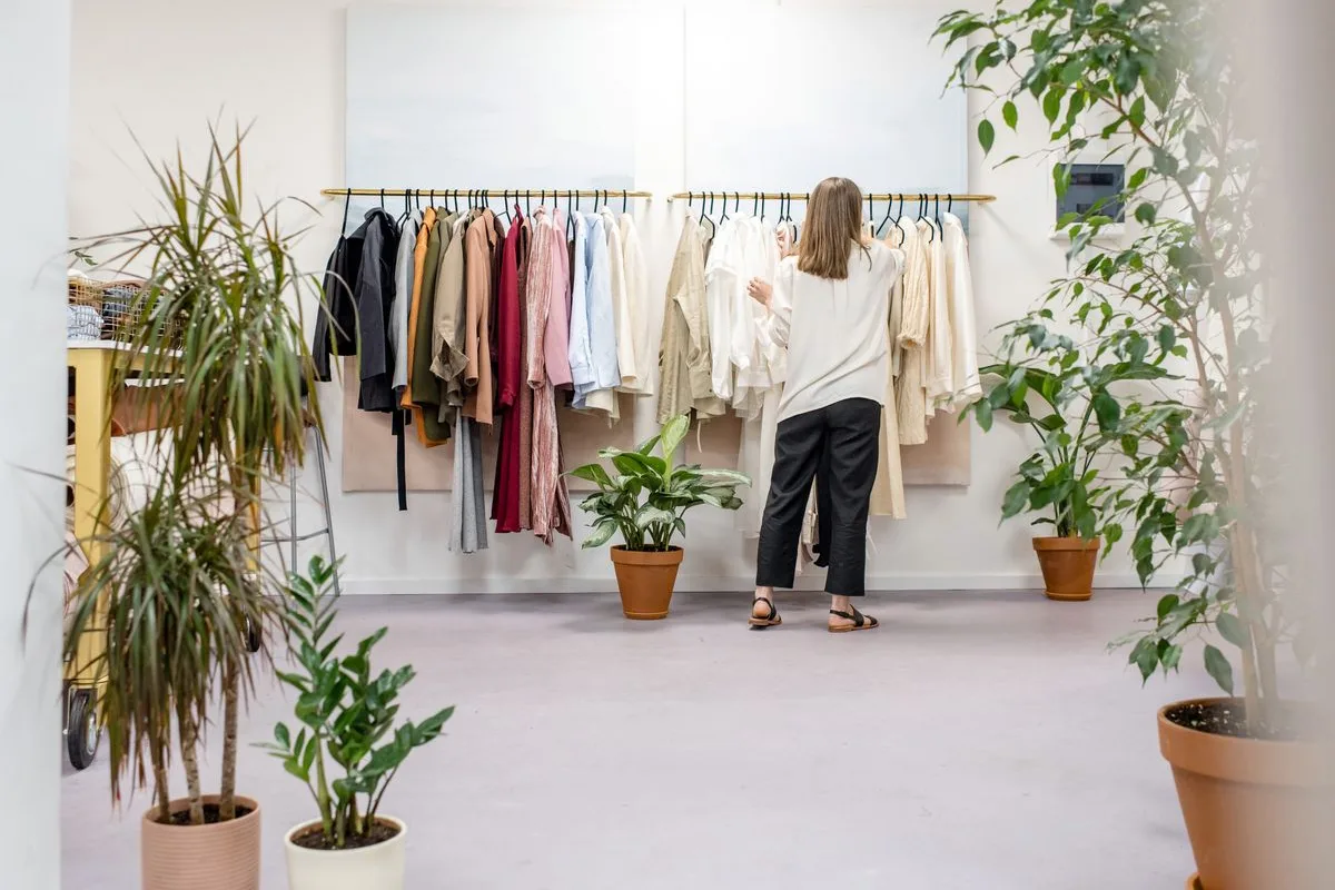 Boutique owner arranging garments in a bright shop
