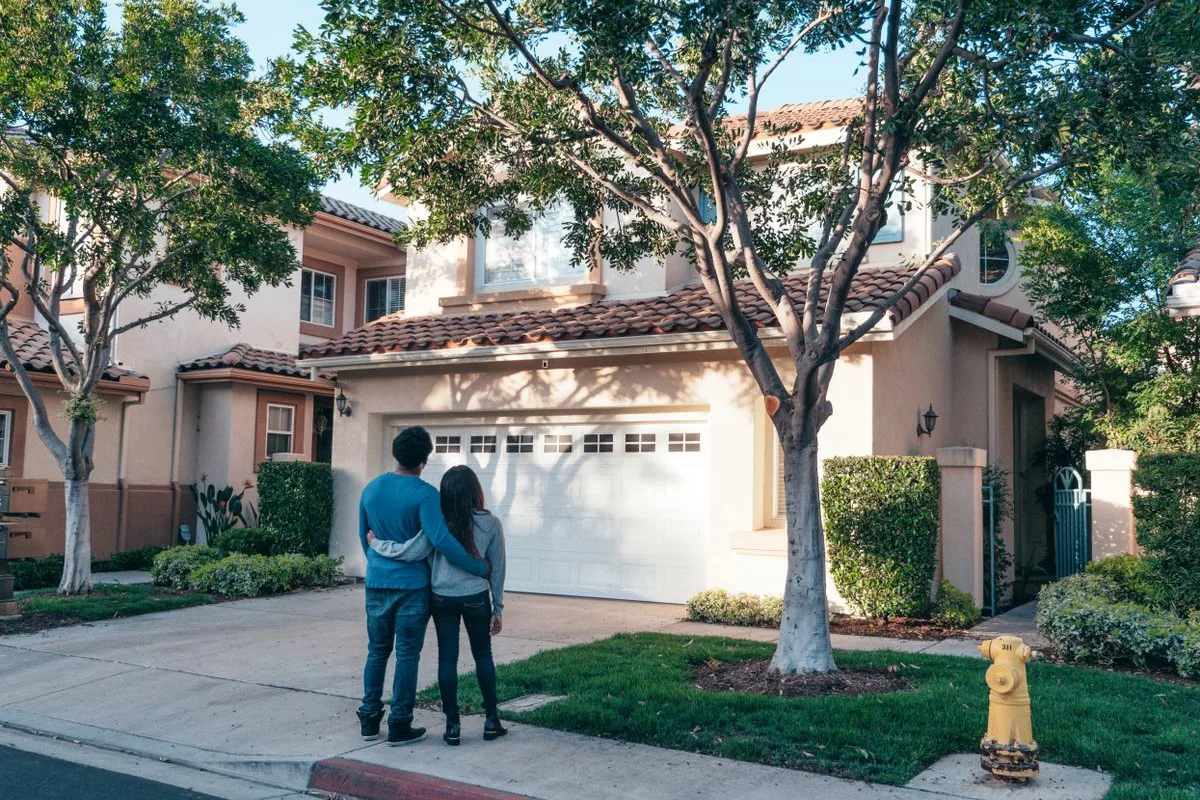 Couple standing arm in arm in front of their home