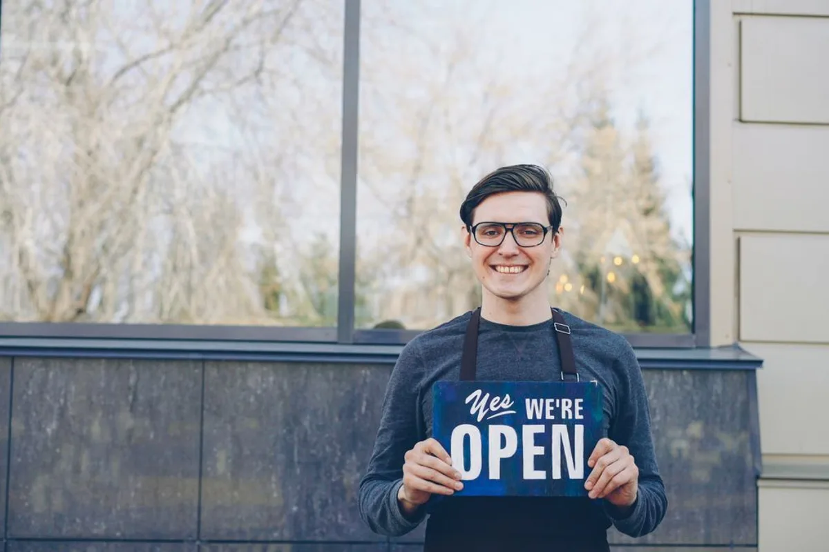 Smiling business owner holding an open sign